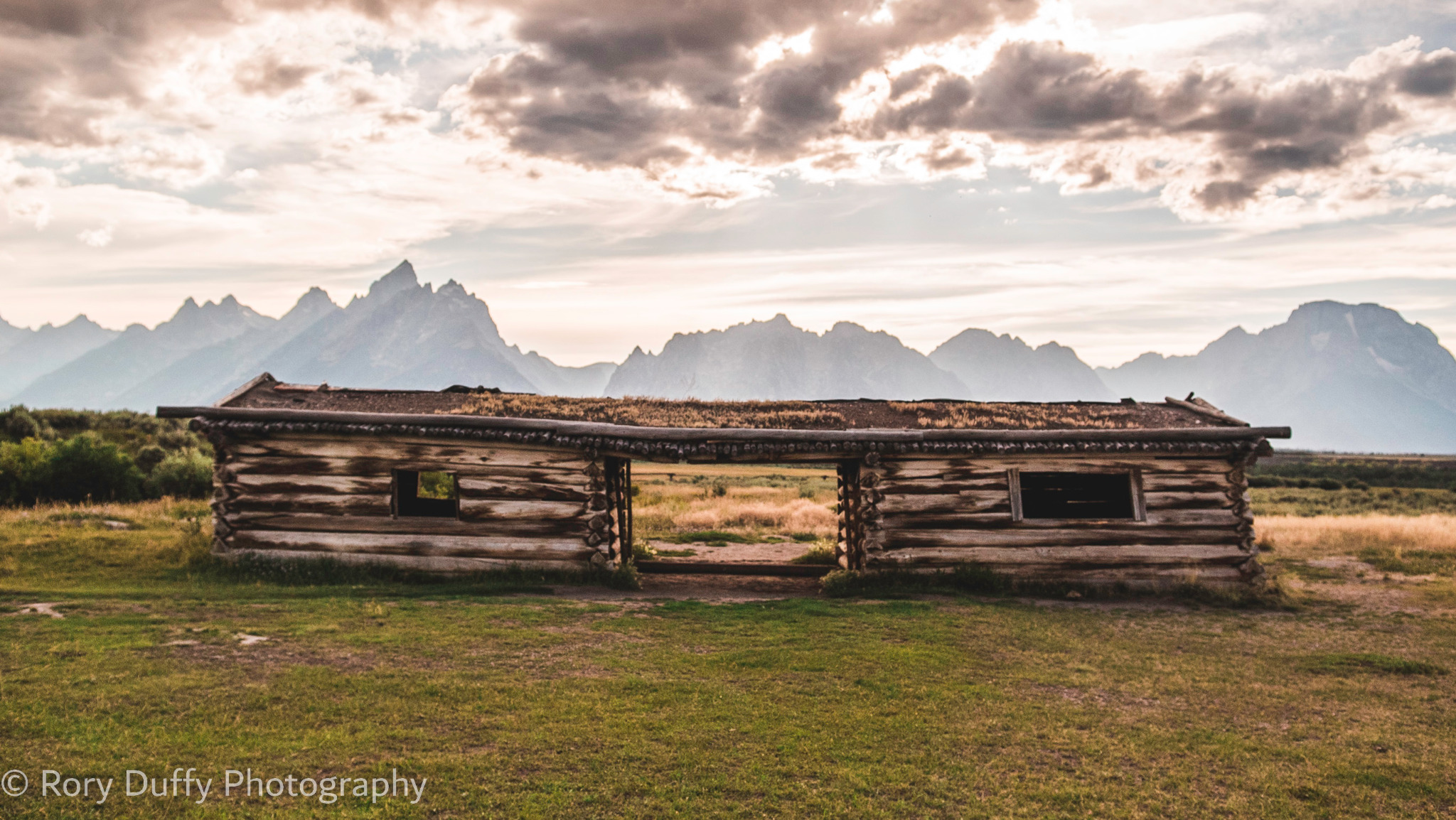Weathered log cabin beneath the Teton Range photographed by Rory Duffy